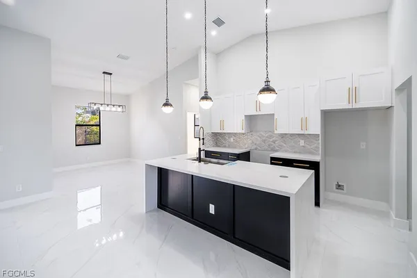 a kitchen with stainless steel appliances granite countertop cabinets a sink a stove a refrigerator and a chandelier
