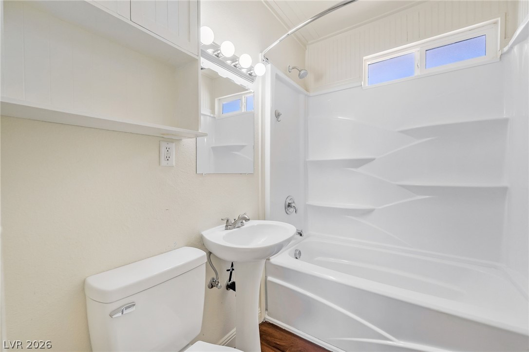 2 California Way Henderson, NV 89015 - Photo 22 of 29 A well-lit bathroom featuring a tub-shower combination, pedestal sink, and convenient shelving.