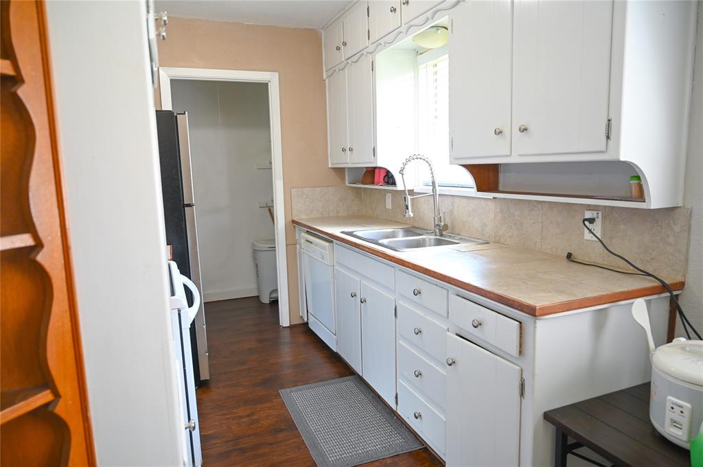 1352 Simpson Drive Hurst, TX 76053 - Photo 18 of 40 Kitchen featuring white cabinetry, dual-basin stainless steel sink, and wood-finish flooring