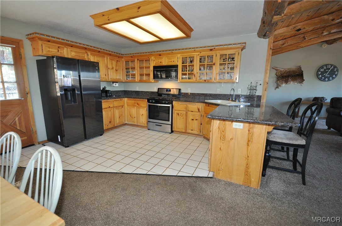1419 Klamath Road Big Bear City, CA 92314 - Photo 17 of 31 a kitchen with stainless steel appliances granite countertop a refrigerator a stove a sink a dining table and chairs with wooden floor