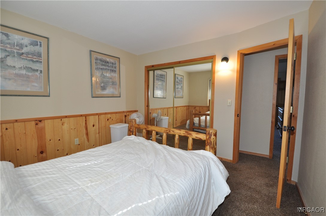 1419 Klamath Road Big Bear City, CA 92314 - Photo 22 of 31 a bedroom with a large bed and a chandelier