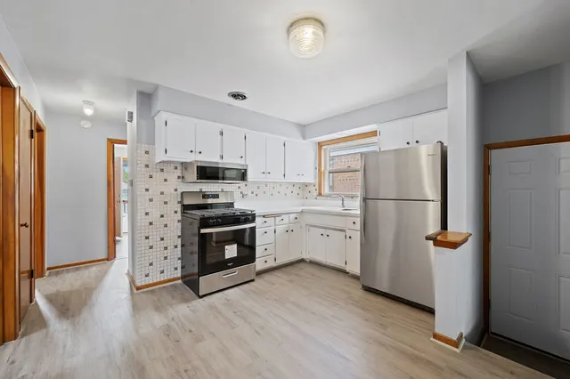 a kitchen with a refrigerator stove and white cabinets