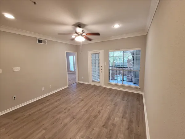 a view of an empty room with a window and wooden floor