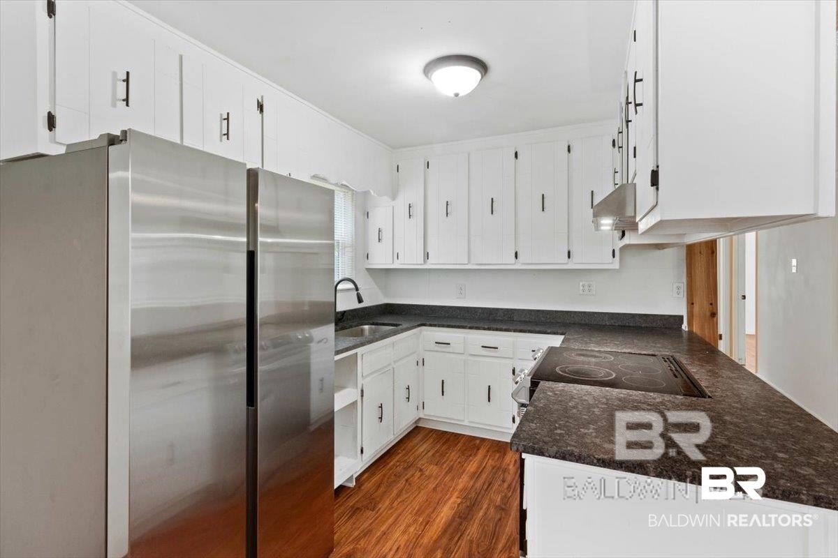 29397 Loper Road Loxley, AL 36551 - Photo 20 of 22 Kitchen with freestanding refrigerator, white cabinets, dark stone countertops, dark wood-style floors, and electric range