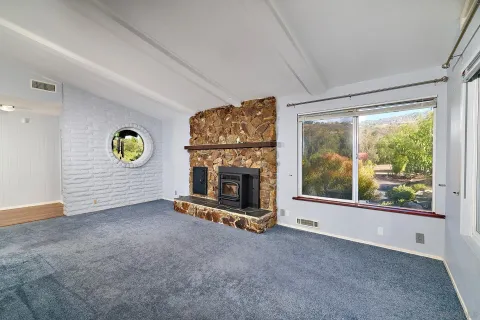 a view of an empty room with a window and fireplace