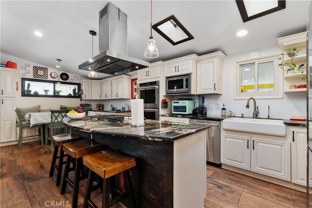 20292 Riverside Drive Newport Beach, CA 92660 - Photo 21 of 23 a kitchen with stainless steel appliances kitchen island a white table and chairs in it