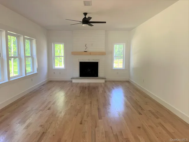 an empty room with wooden floor fireplace and windows
