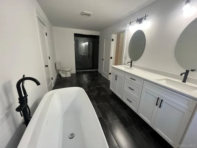 a bathroom with a double vanity sink mirror and toilet