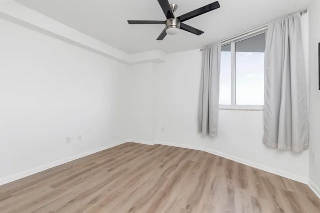 a view of empty room with wooden floor and fan