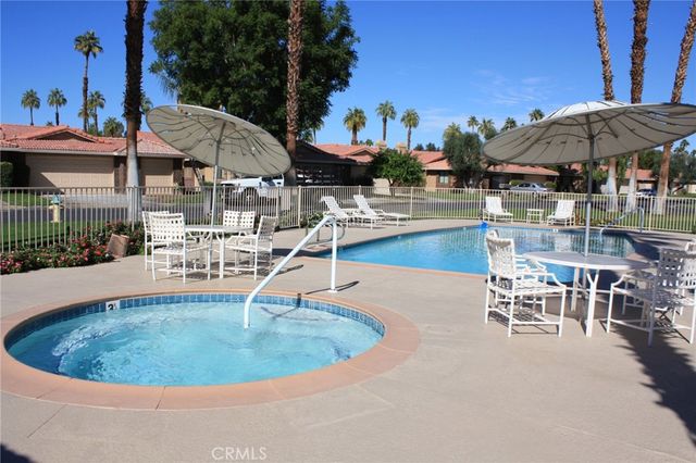 a view of a swimming pool with lawn chairs under an umbrella