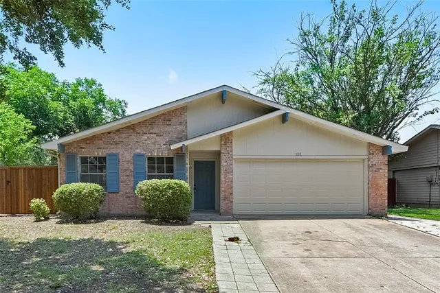 a view of a yard in front of a house with plants and large tree