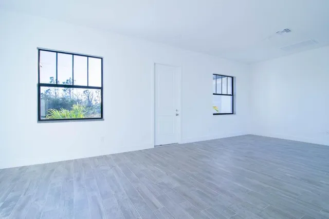 an empty room with wooden floor and windows