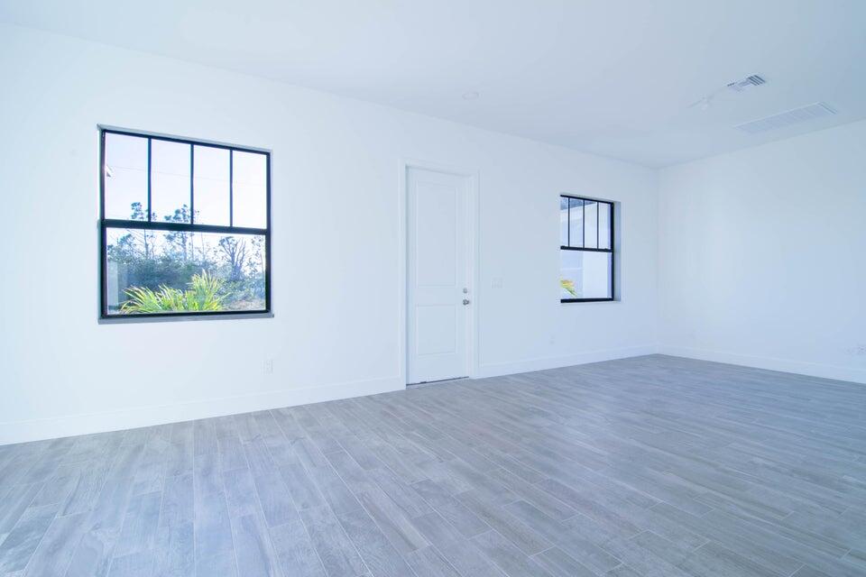 8126 Thruso Road Port Charlotte, FL 33981 - Photo 13 of 32 an empty room with wooden floor and windows