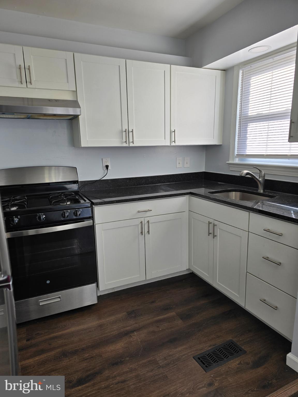 3910 74th Avenue Hyattsville, MD 20784 - Photo 4 of 23 a kitchen with granite countertop white cabinets and a stove with wooden floor
