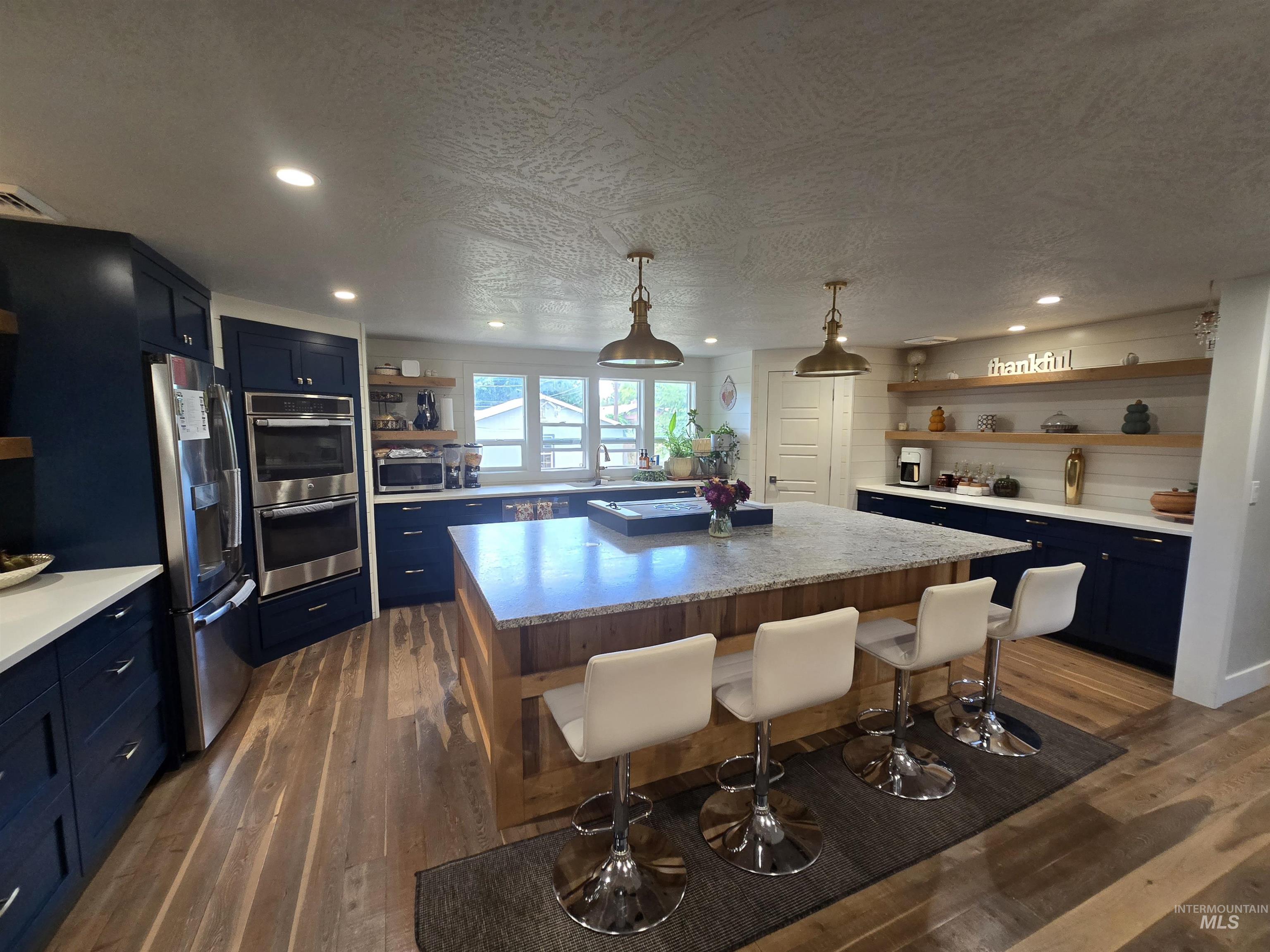 1265 West 1st Street Weiser, ID 83672 - Photo 12 of 23 Kitchen featuring open shelves, blue cabinetry, pendant lighting, a kitchen island, and stainless steel appliances