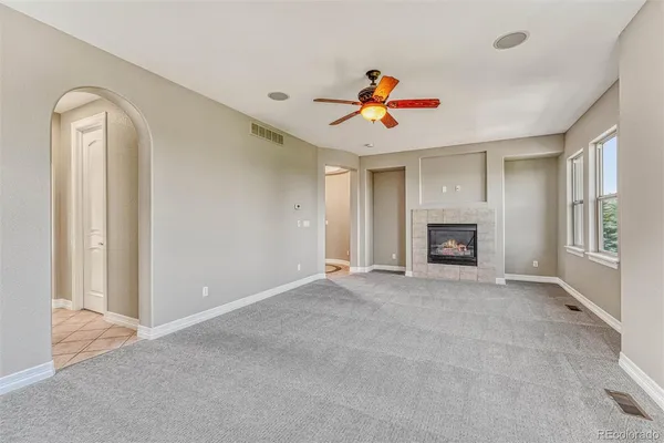 a view of an empty room with chandelier fan and fire place