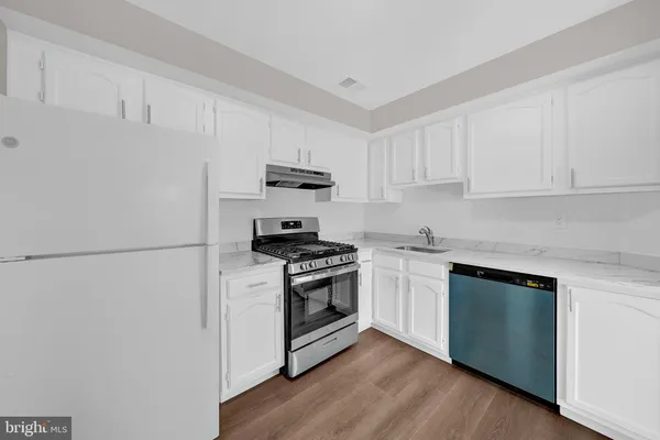 a kitchen with stainless steel appliances granite countertop white cabinets and a stove a oven with white countertops