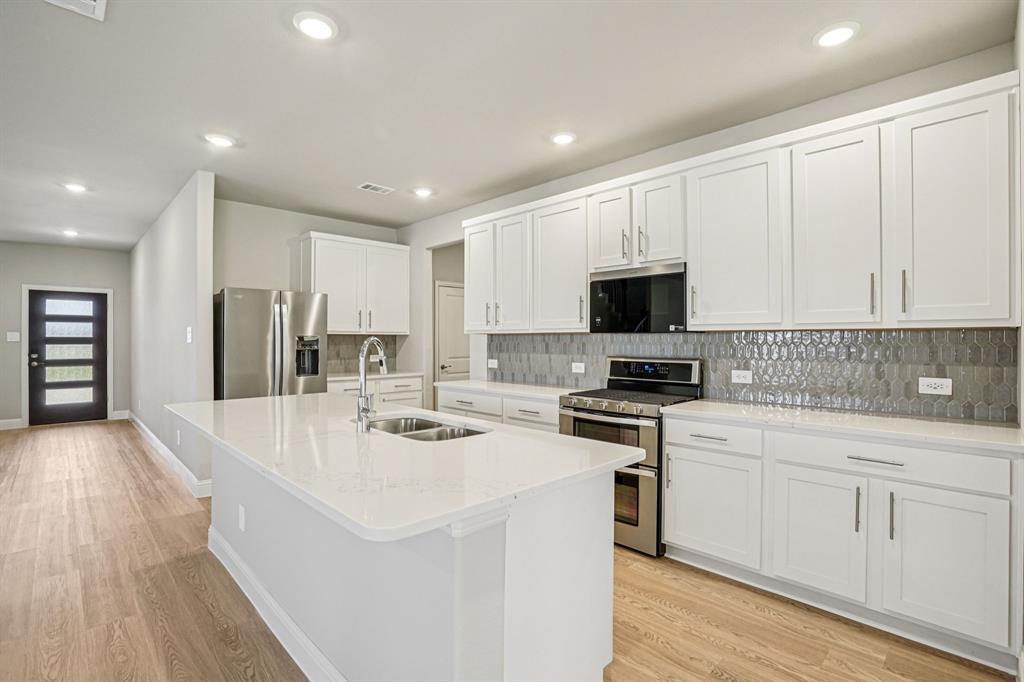 a kitchen with a sink a stove a refrigerator and white cabinets