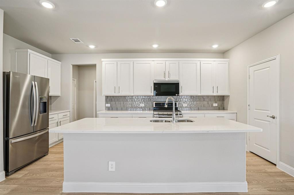 2621 Grand Cyn Street Anna, TX 75409 - Photo 5 of 37 a kitchen with kitchen island a sink stainless steel appliances and cabinets