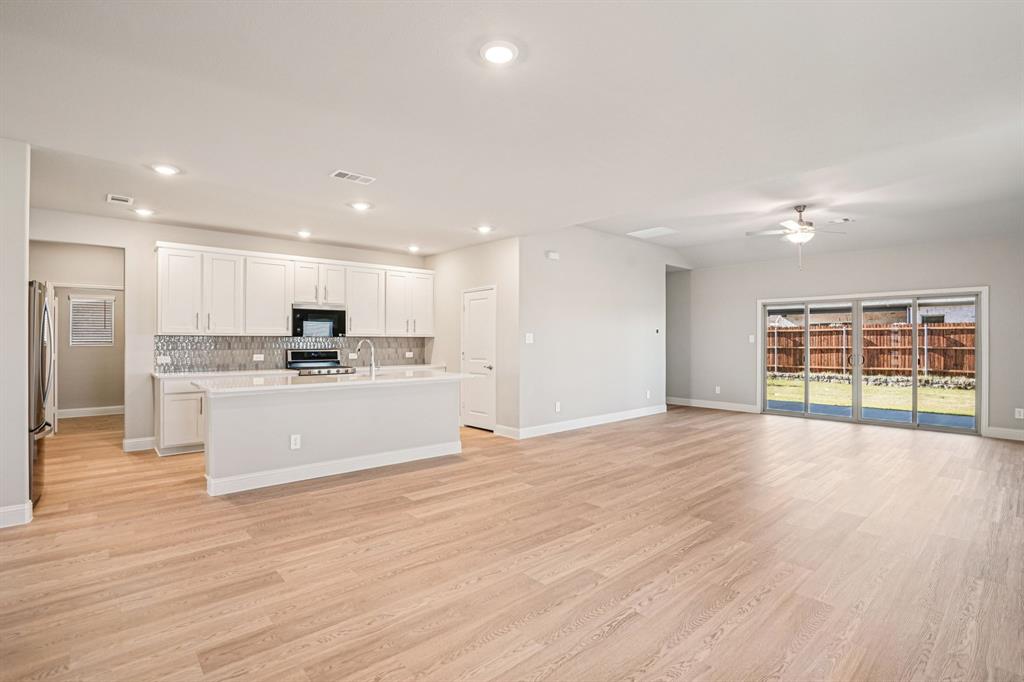 2621 Grand Cyn Street Anna, TX 75409 - Photo 9 of 37 a large kitchen with kitchen island a sink wooden floor and stainless steel appliances