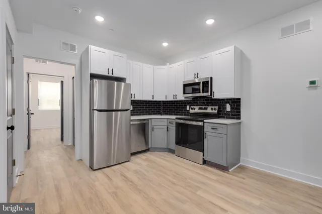 a kitchen with granite countertop a refrigerator and a stove top oven