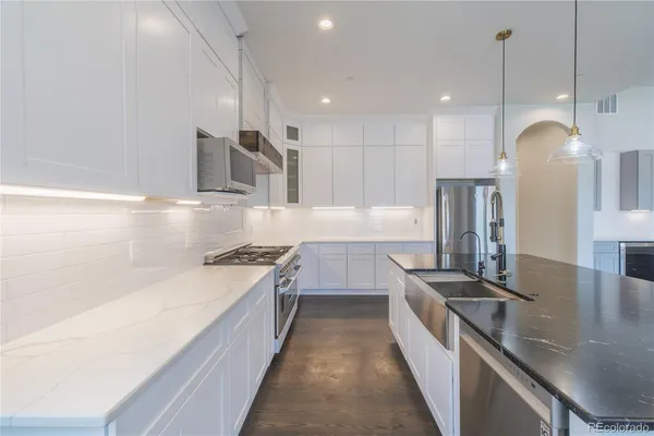 a large kitchen with stainless steel appliances granite countertop a lot of counter space a sink and a wooden floors