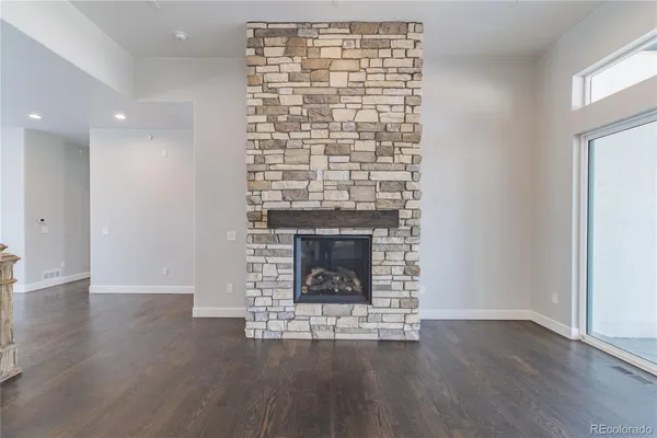 a view of an empty room with wooden floor fireplace and a window