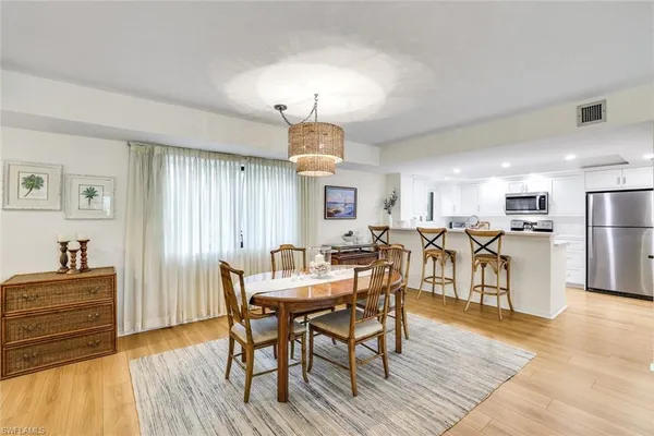 a kitchen with stainless steel appliances granite countertop a sink a stove top oven a dining table and chairs