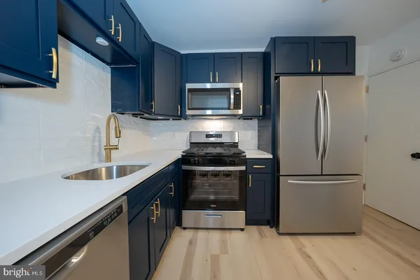 a kitchen with kitchen island granite countertop a refrigerator and a sink