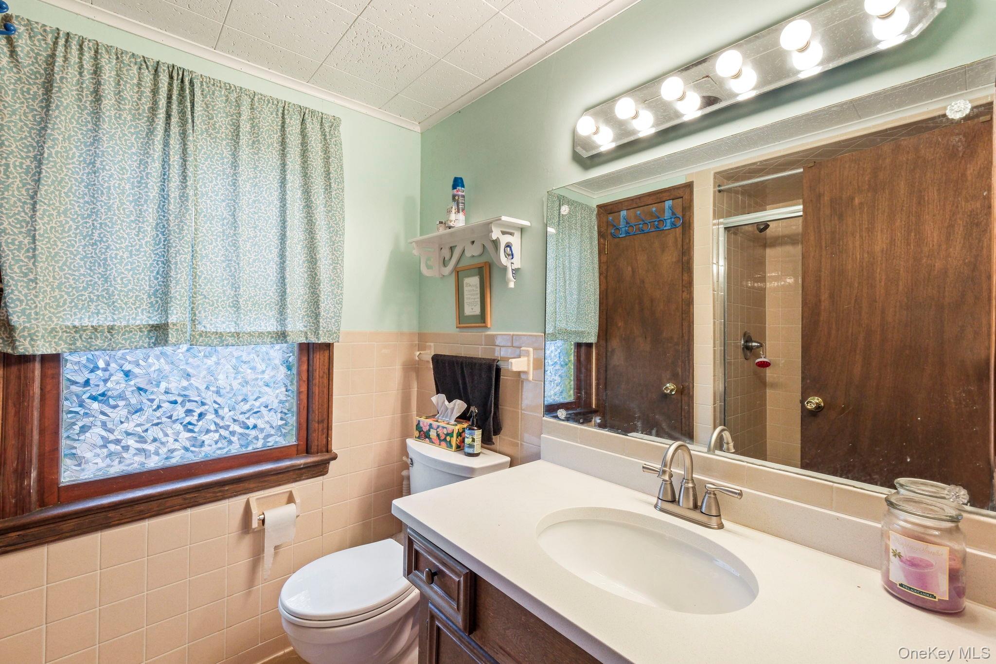 184 Yankee Lake Road Wurtsboro, NY 12790 - Photo 13 of 27 Bathroom with vanity, tile walls, crown molding, a stall shower, and a wainscoted wall