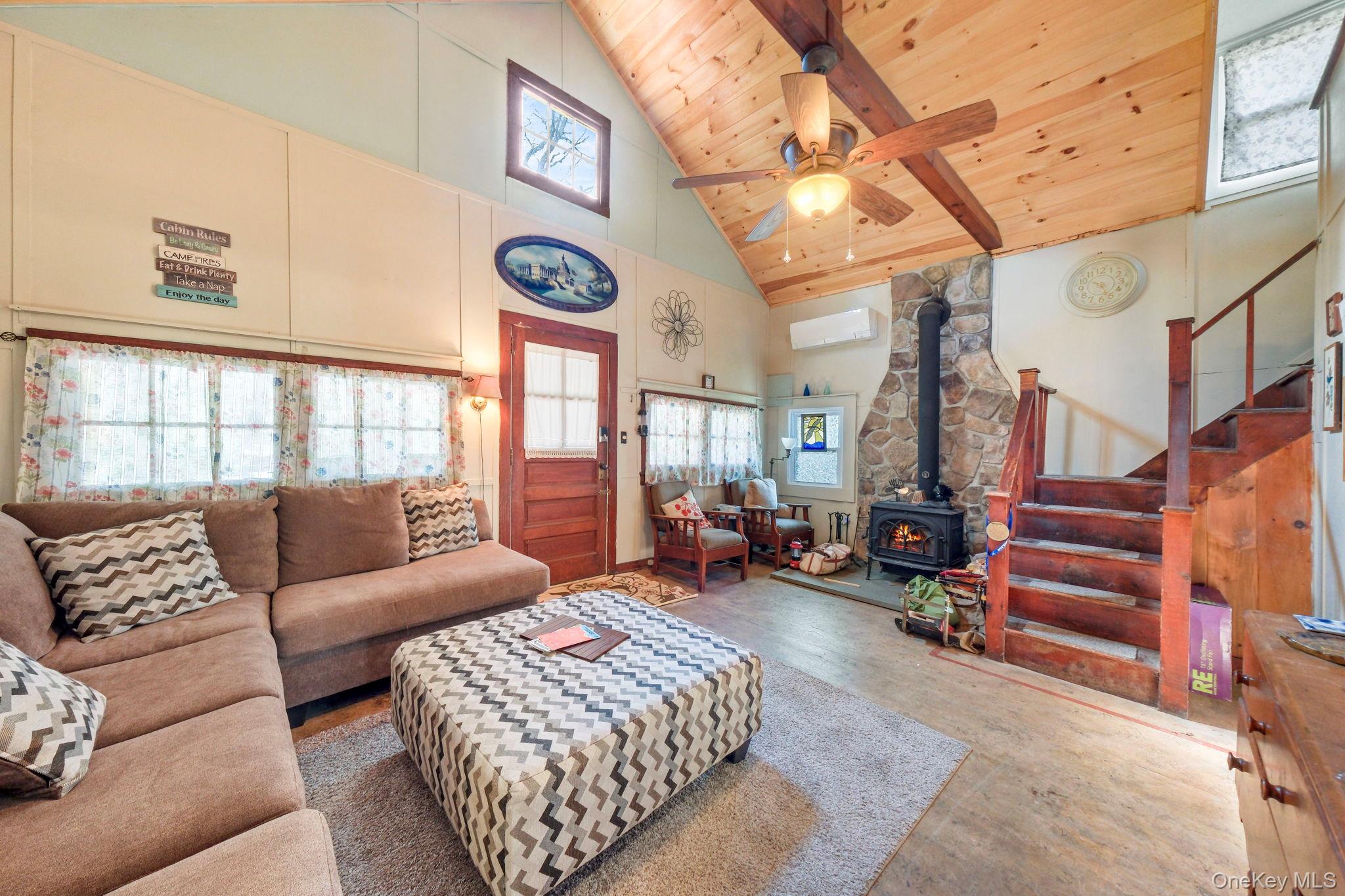 184 Yankee Lake Road Wurtsboro, NY 12790 - Photo 2 of 27 Living room featuring a wood stove, wood finished floors, healthy amount of natural light, ceiling fan, and a high wooden beamed ceiling