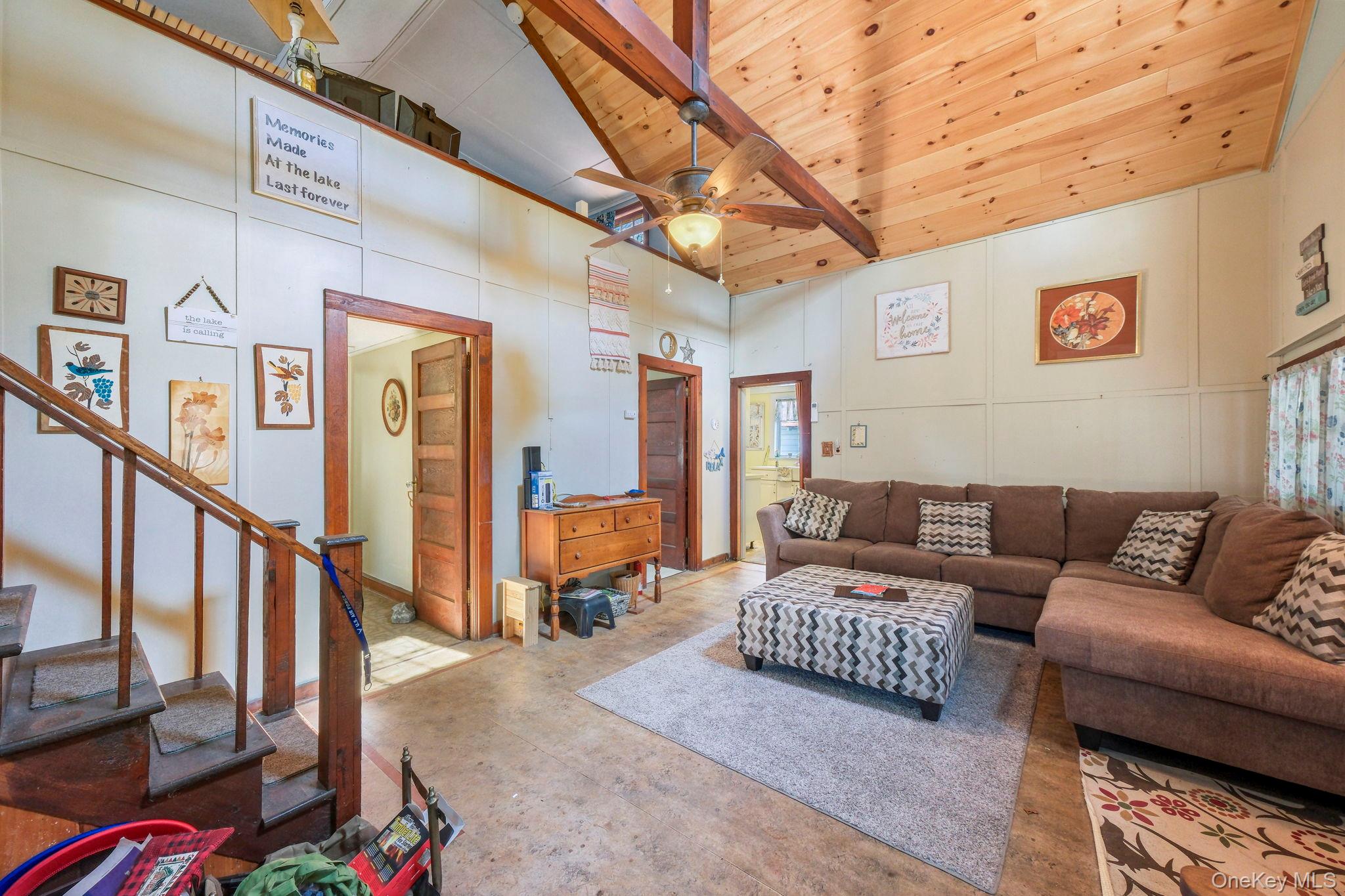 184 Yankee Lake Road Wurtsboro, NY 12790 - Photo 4 of 27 Living room featuring a ceiling fan, a decorative wall, concrete flooring, and a vaulted wood ceiling