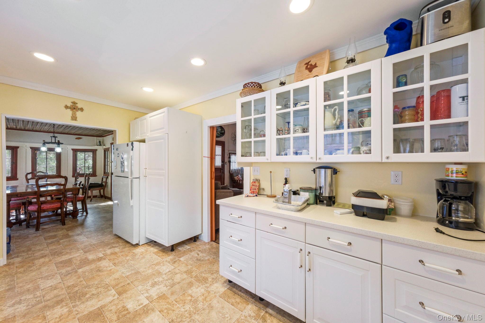 184 Yankee Lake Road Wurtsboro, NY 12790 - Photo 6 of 27 Kitchen with glass fronted cabinets, white cabinets, freestanding refrigerator, crown molding, and recessed lighting