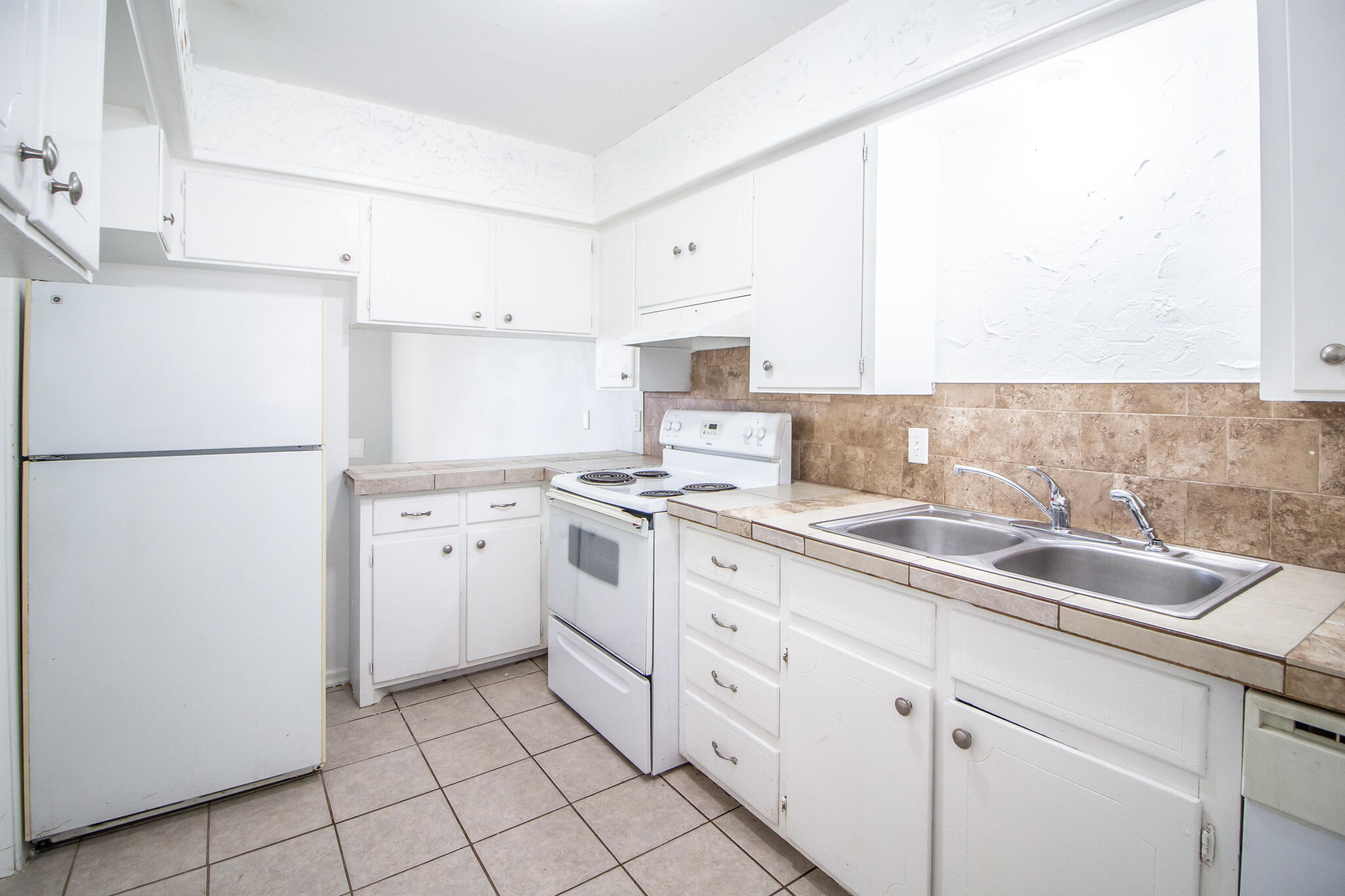 2105 49th Street Lubbock, TX 79412 - Photo 7 of 31 a kitchen with a sink a refrigerator and cabinets