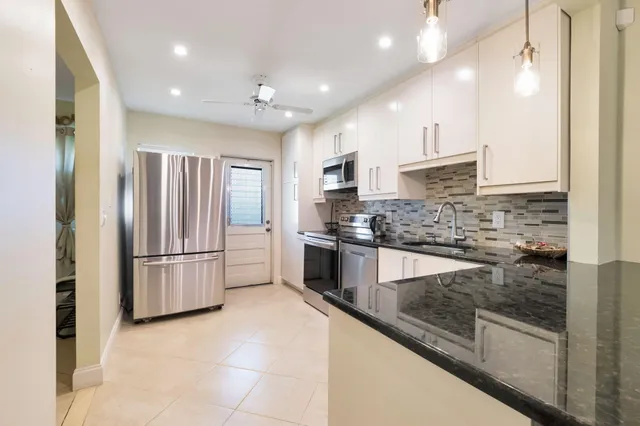 a kitchen with stainless steel appliances granite countertop a refrigerator a stove and a sink