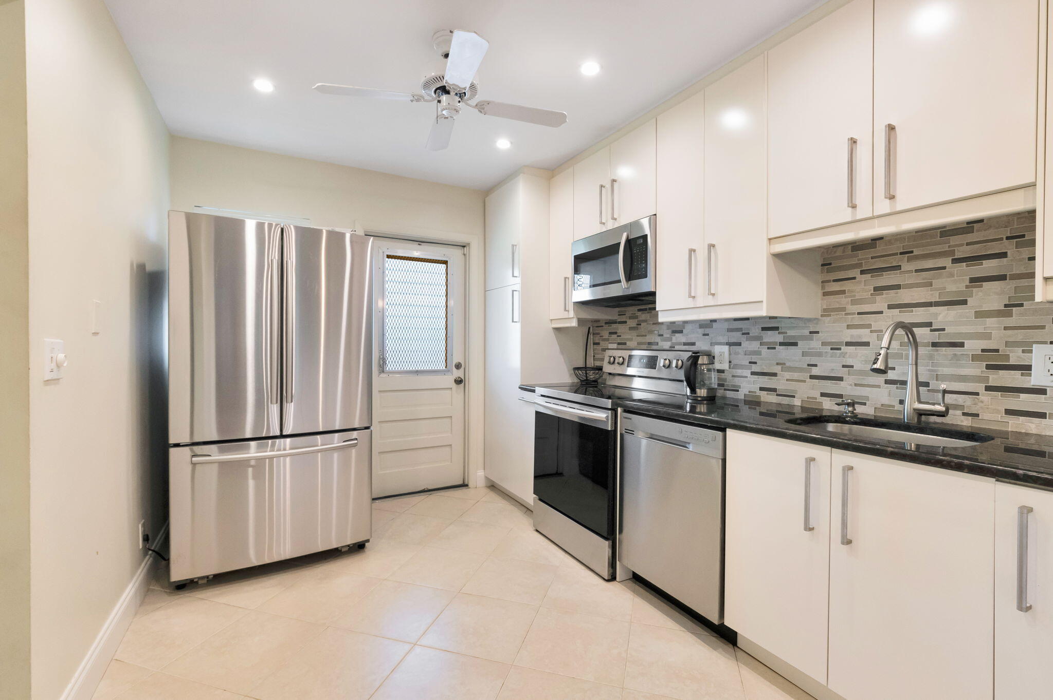 1700 Dover Road, Unit 204A Delray Beach, FL 33445 - Photo 5 of 33 a kitchen with granite countertop white cabinets and stainless steel appliances