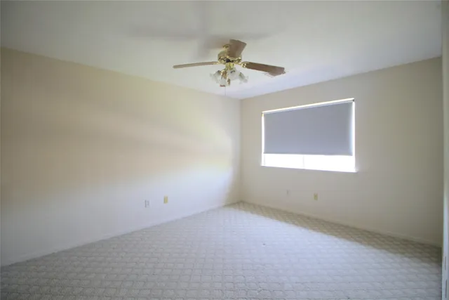 an empty room with a window and a fan