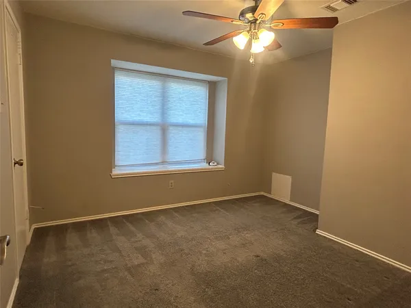 an empty room with a window and a fan