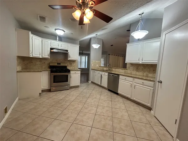 a large kitchen with cabinets a sink a stove a oven a dining table and chairs