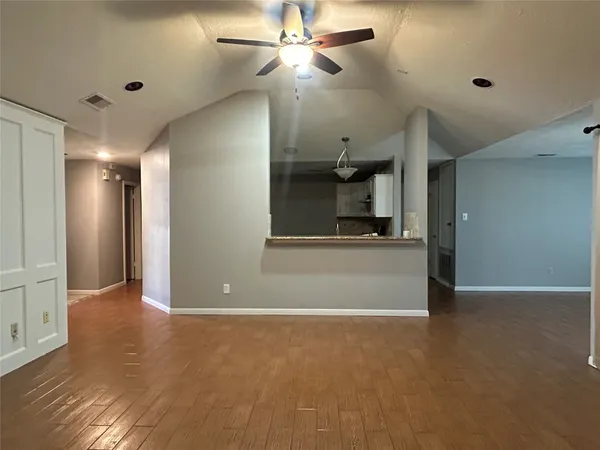 a view of an empty room with kitchen and a window