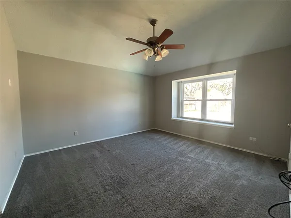 an empty room with windows and fan