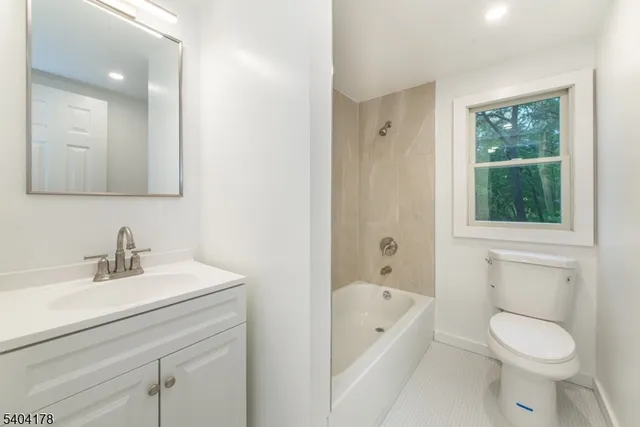 a bathroom with a toilet a sink a tub and mirror