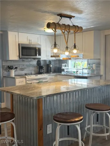 a kitchen with granite countertop a table chairs stove and cabinets