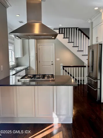 a kitchen with stainless steel appliances granite countertop a stove and a white cabinets
