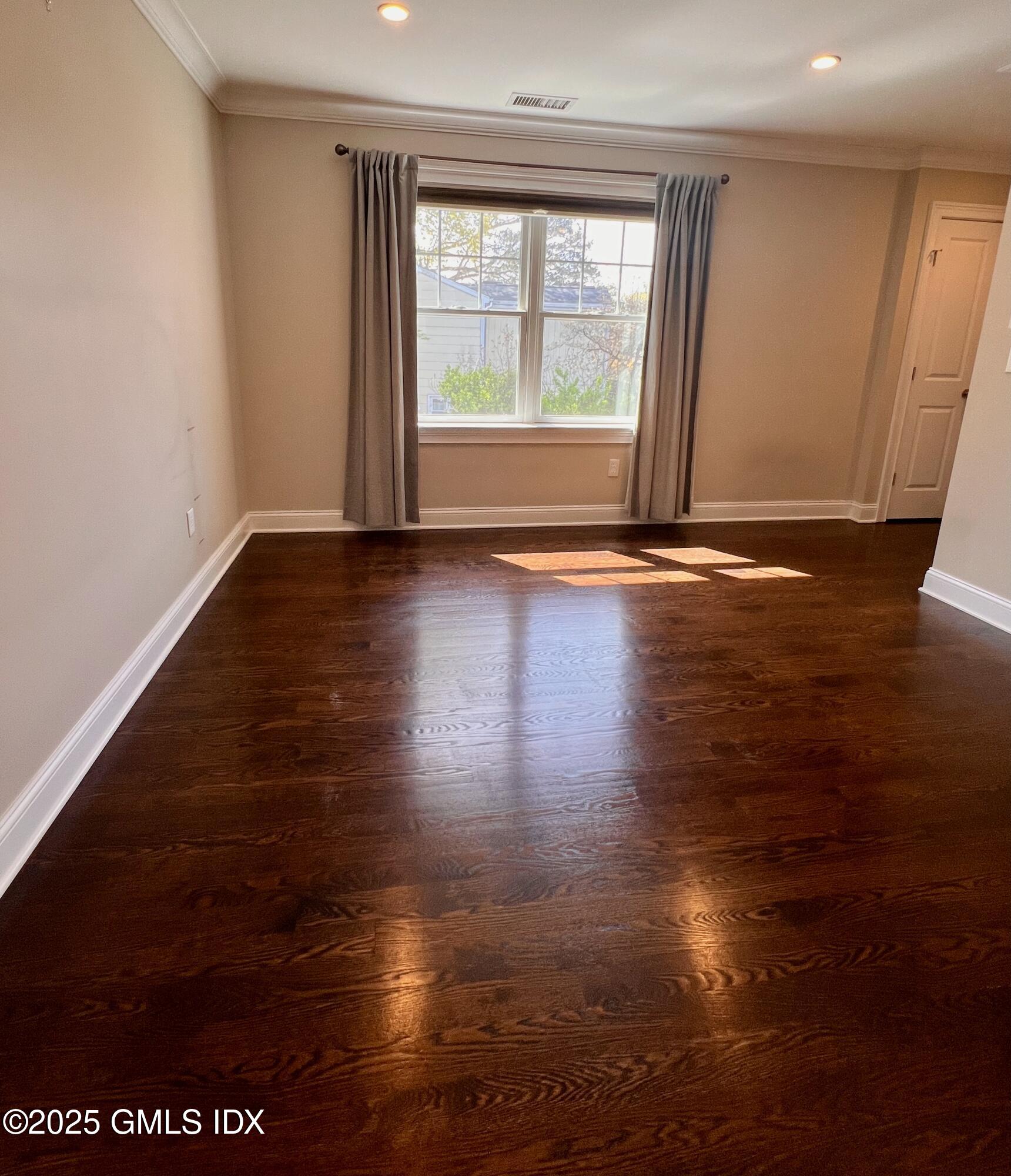 31 Moshier Street, Unit B Greenwich, CT 06831 - Photo 12 of 28 an empty room with wooden floor and windows with curtains