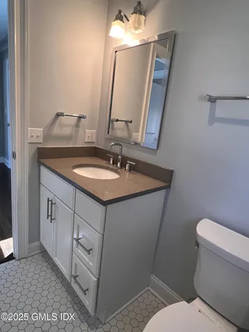 a bathroom with a granite countertop toilet sink and mirror