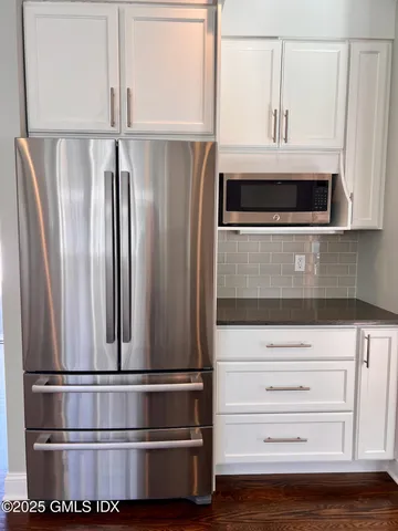 a view of kitchen with stainless steel appliances wooden floor and cabinets