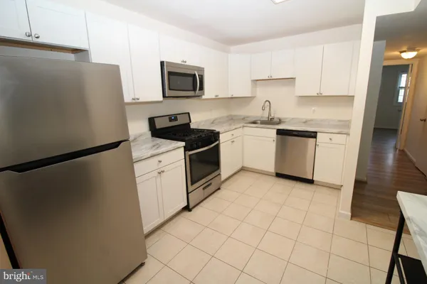 a kitchen with a sink a refrigerator a stove top oven and cabinets