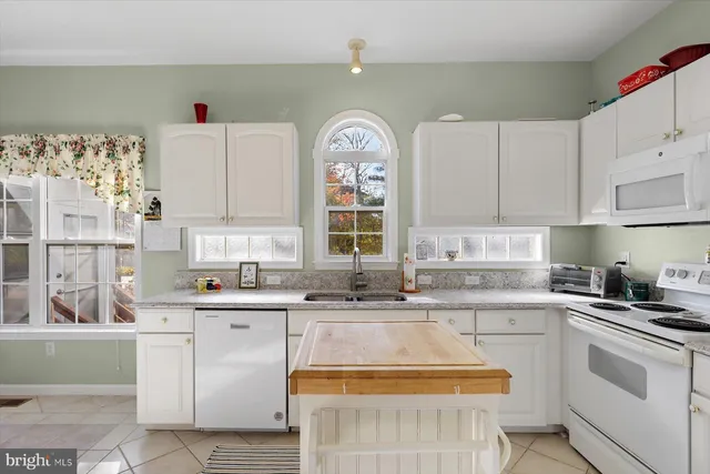 a spacious bedroom with a bed a chandelier and a large window