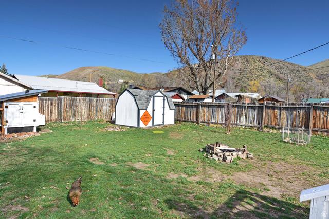 315 Park Street Inkom, ID 83245 - Photo 27 of 28 Expansive backyard with a green lawn, wood privacy fence, and a stone-lined fire pit
